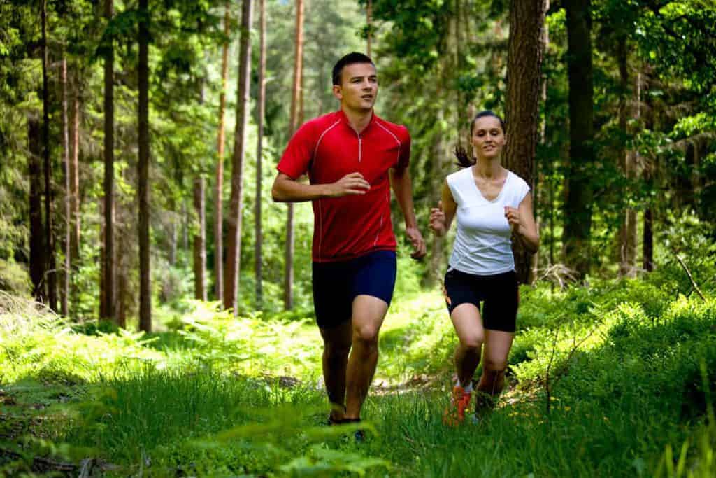  мъж и жена тичат през гората