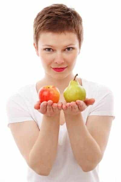  eine Frau behält einen Apfel und eine Birne