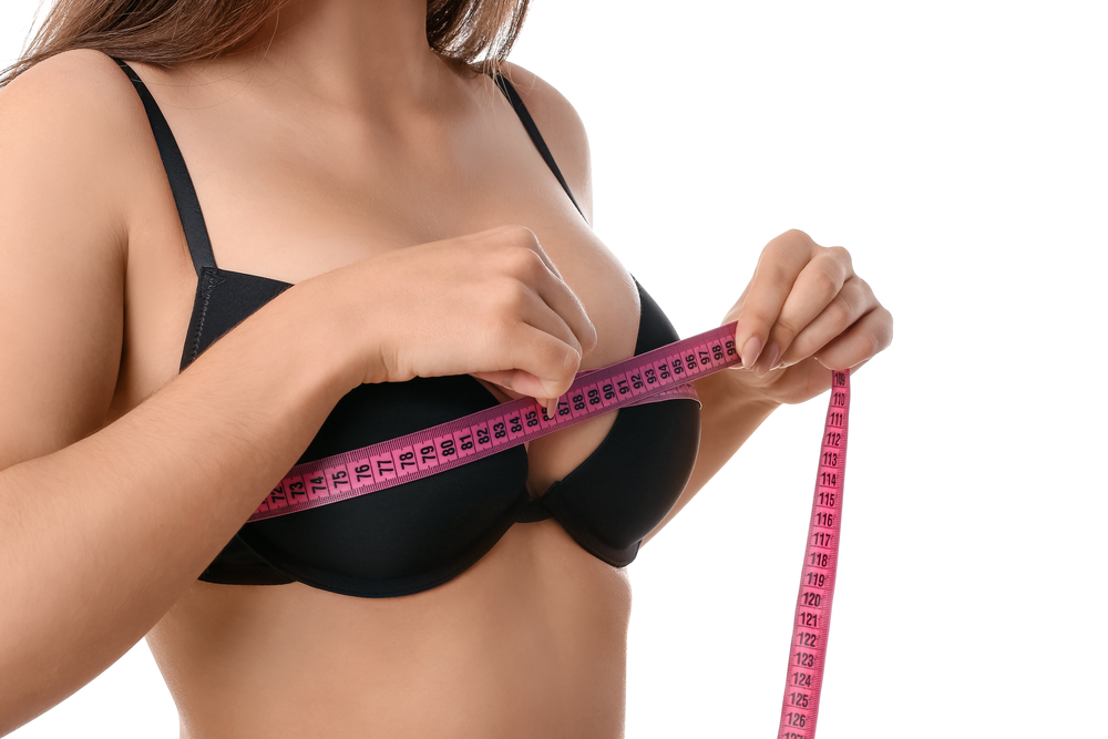  en kvinde måler sin bryststørrelse
