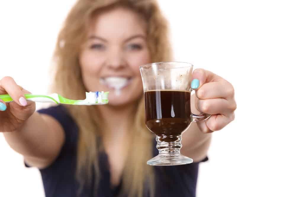  moteris su kava ir dantų šepetėliu