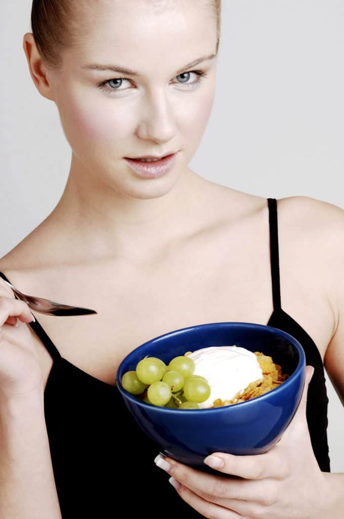  sieviete ēd graudaugu pārslas ar augļiem