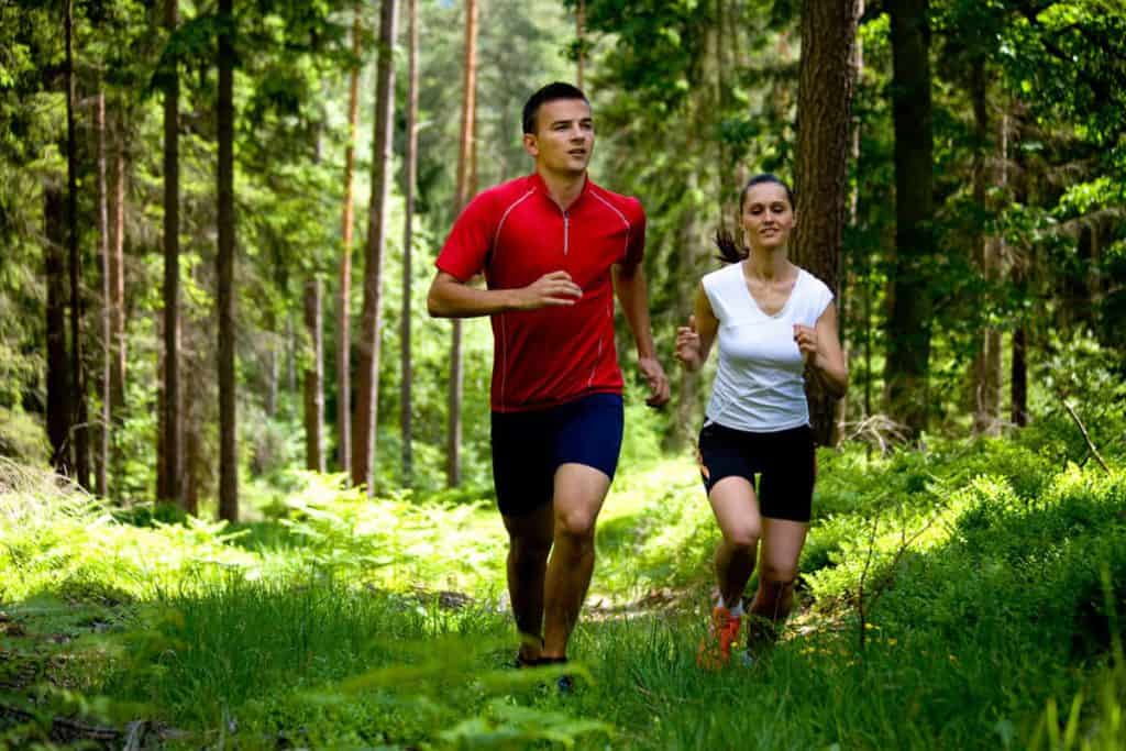  een man en een vrouw rennen door het bos