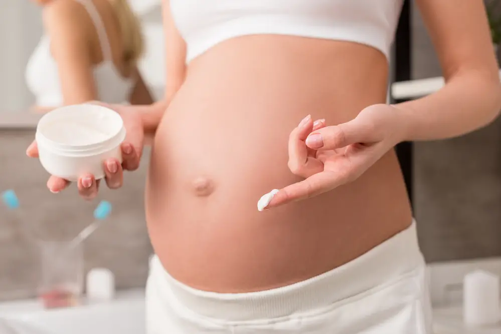  zwangere vrouwen smeren een crème op hun buik