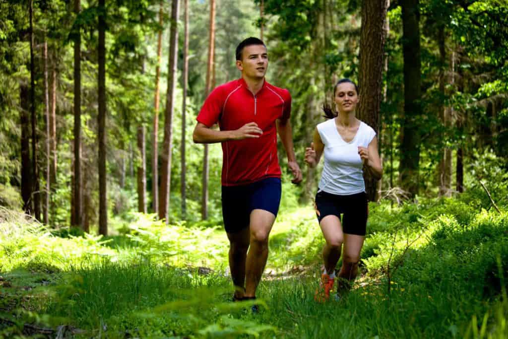  en man och en kvinna springer genom skogen